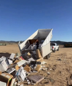 A dump trailer unloading a large pile of boxes and debris, showcasing a junk removal job by richartehelps in Scottsdale, AZ.