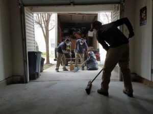 The Junk Unlimited Junk Removal crew sweeping a garage floor after completing a junk removal job in Laurel, MD.