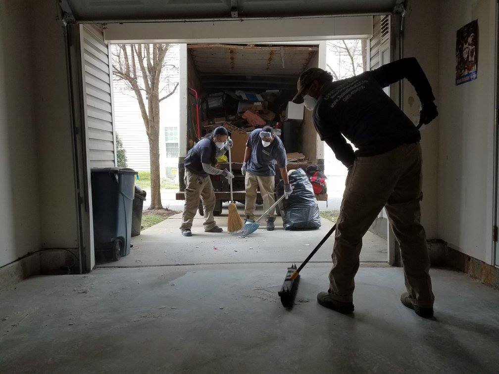 The Junk Unlimited Junk Removal crew sweeping a garage floor after completing a junk removal job in Laurel, MD.