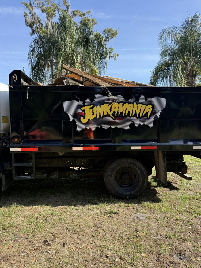 A Junkamaniafl truck with its bed filled with wood debris from a junk removal service in Greenwood, IN.