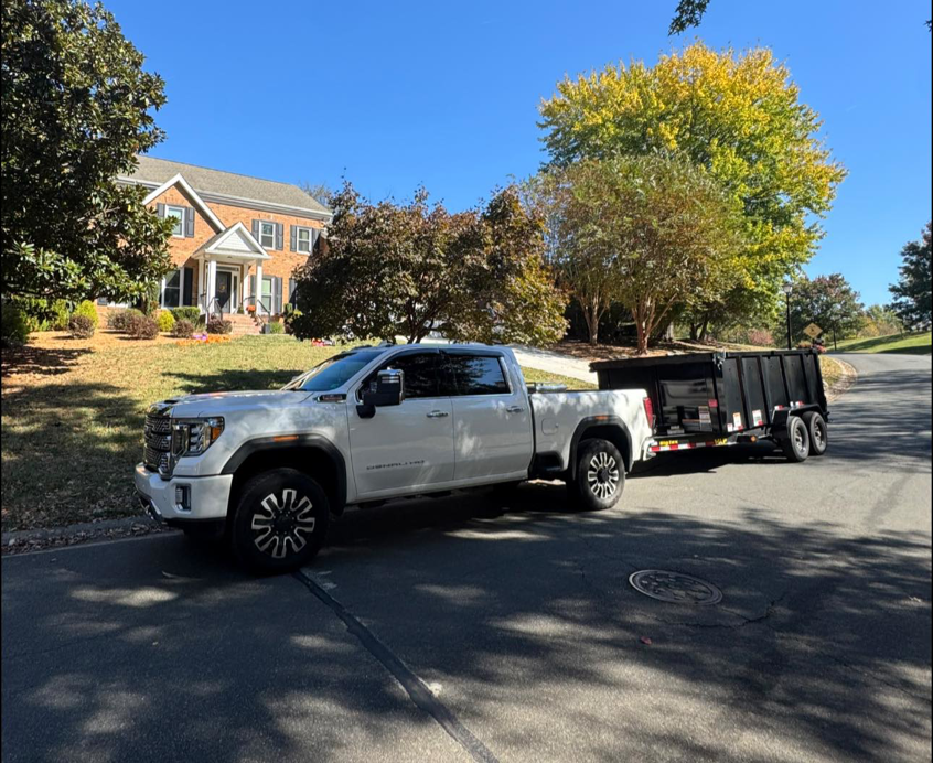 A Junkjet pickup truck with an empty dump trailer parked on a residential street in Charlotte, NC.