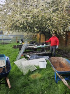 A Junkzilla Inc. worker standing by a pile of glass, metal, and other debris in a grassy area for removal in Everett, WA.