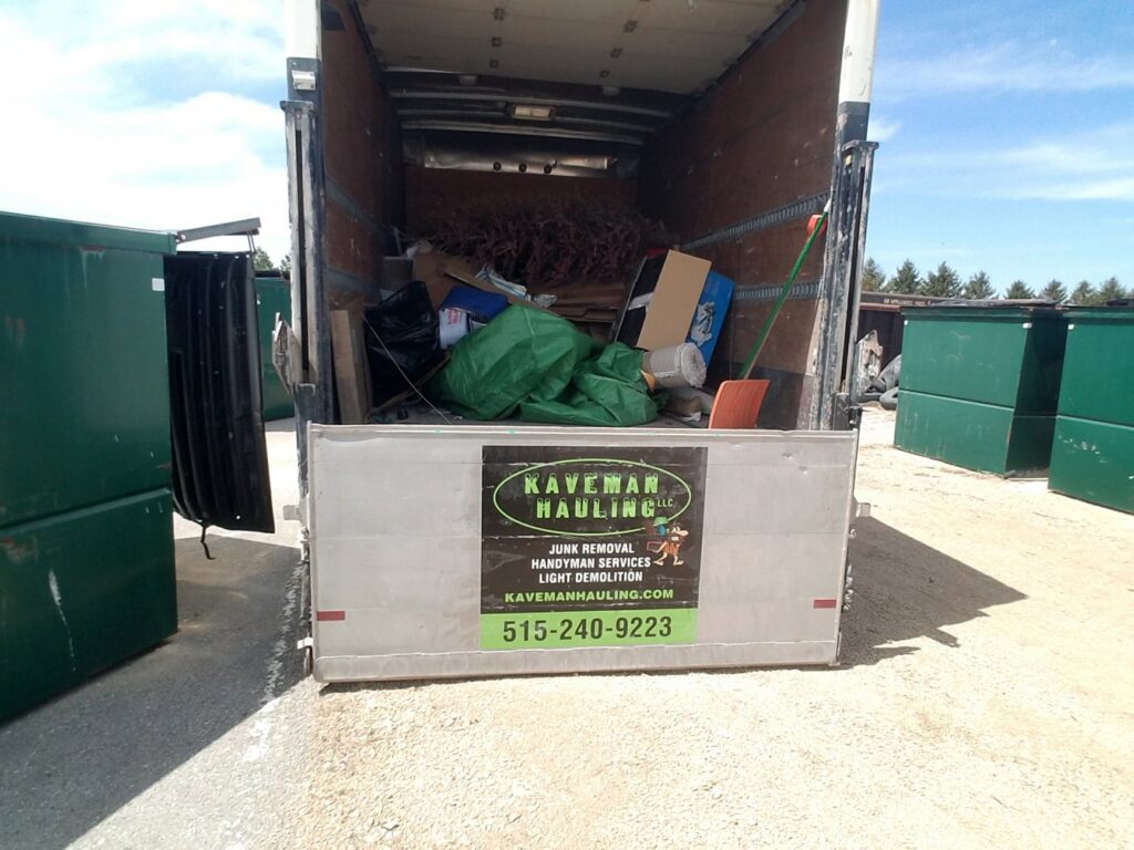 A Kaveman Hauling LLC truck loaded with various items and junk, ready for transport in Ankeny, IA.