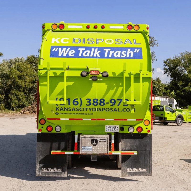 A green KC Disposal roll-off dumpster placed in a residential driveway in Kansas City, KS.