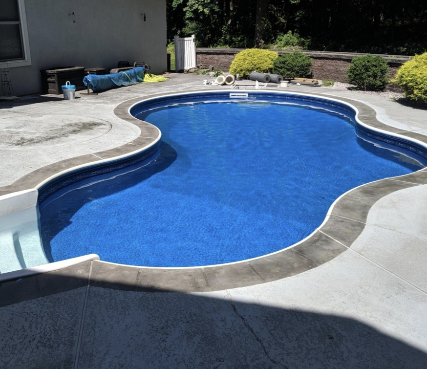 A beautiful kidney-shaped pool with a new liner and coping installed by MVP Pools in Woodbridge, NJ