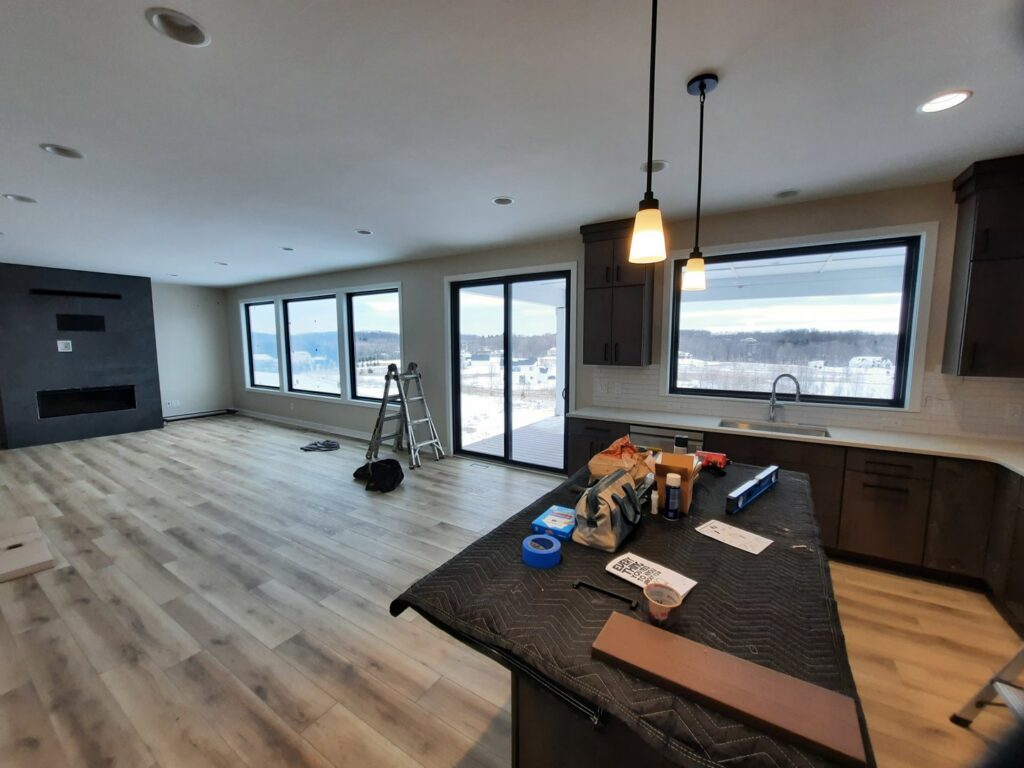 Kitchen and living area finishing work in progress with tools and a ladder by Woods Builders in Grand Rapids, MI.