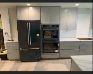 Kitchen renovation featuring new gray cabinets, a refrigerator, and built-in ovens, installed by Fisher Construction, LLC in Selah, WA.