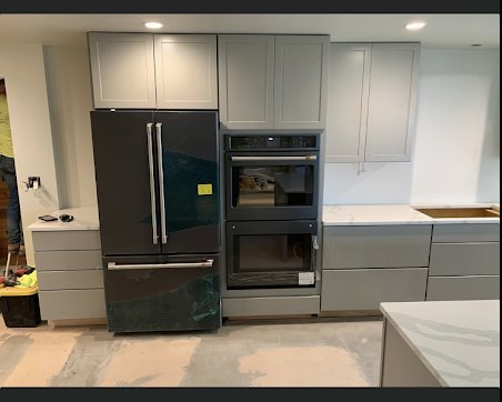 Kitchen renovation featuring new gray cabinets, a refrigerator, and built-in ovens, installed by Fisher Construction, LLC in Selah, WA.