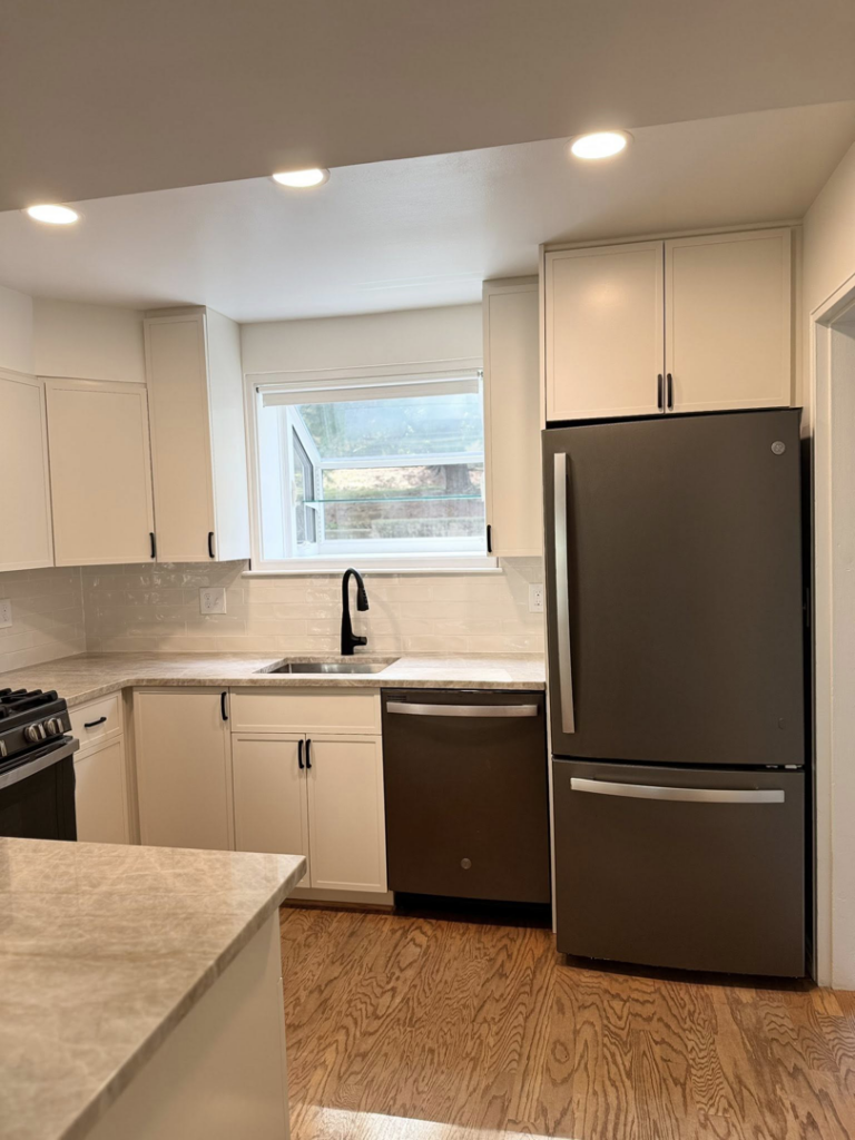 A modern kitchen featuring white cabinets, a sink with a black faucet, a dishwasher, and a refrigerator, installed by NC Home Remodeling and Custom Cabinetry in Alexandria, VA.