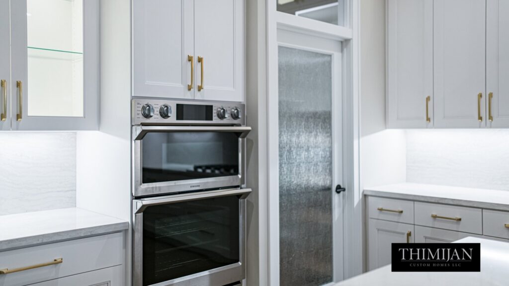 A modern kitchen featuring built-in stainless steel ovens and white shaker cabinets, installed by Thimijan Custom Homes LLC in Rochester, MN