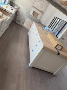A kitchen area with newly installed hardwood floors and a protected island by Heritage Floors of Hanover LLC in Mechanicsville, VA.