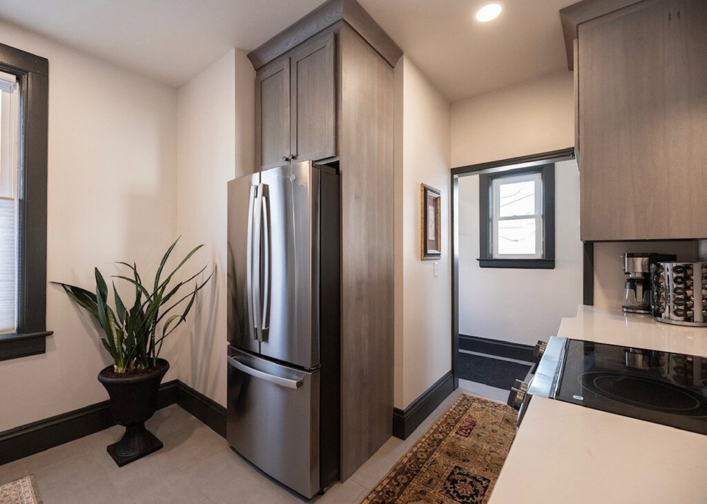 A renovated kitchen area featuring a stainless steel refrigerator, custom cabinets, and a decorative plant, completed by Orion Construction Services in Duluth, MN.