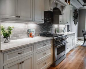 A kitchen with white cabinets, light countertops, and a grey subway tile backsplash installed by Counter Fitters in Savannah, GA