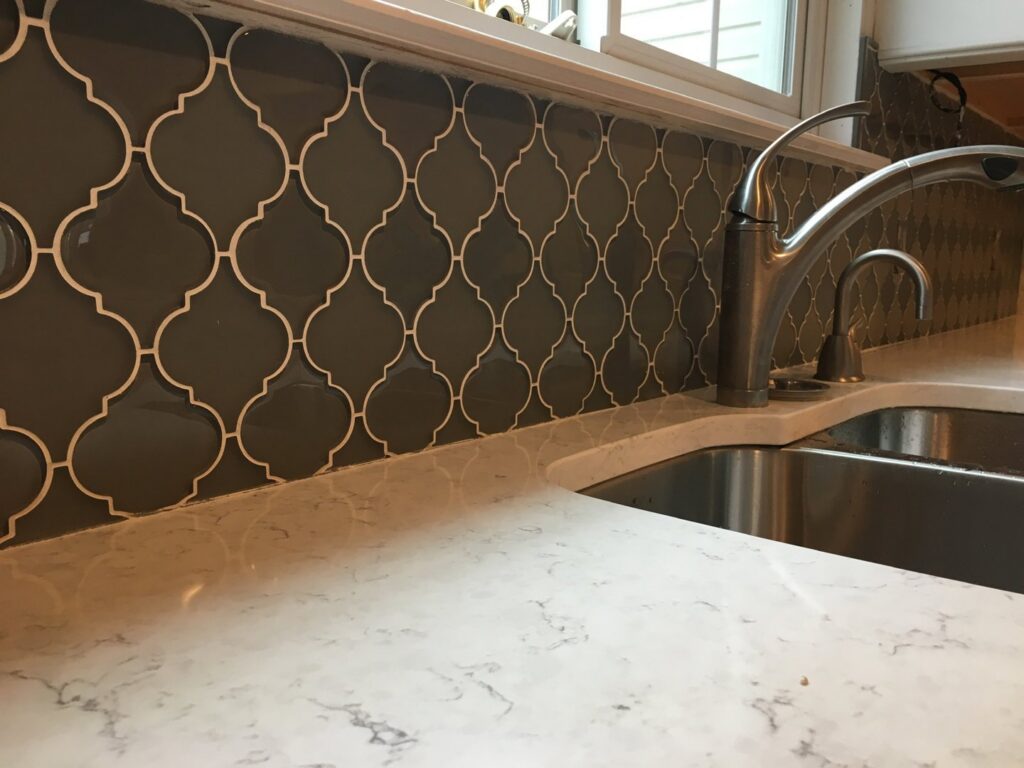 A newly installed kitchen backsplash with an arabesque tile pattern and a modern faucet by Better Than Your Last Handyman in St. Charles, MO.