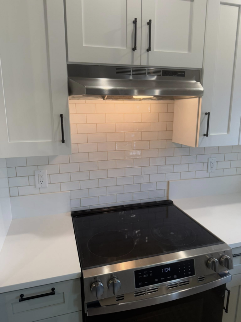 A newly installed white subway tile kitchen backsplash and range hood by Burrell Tile INC in Cottage Grove, OR.