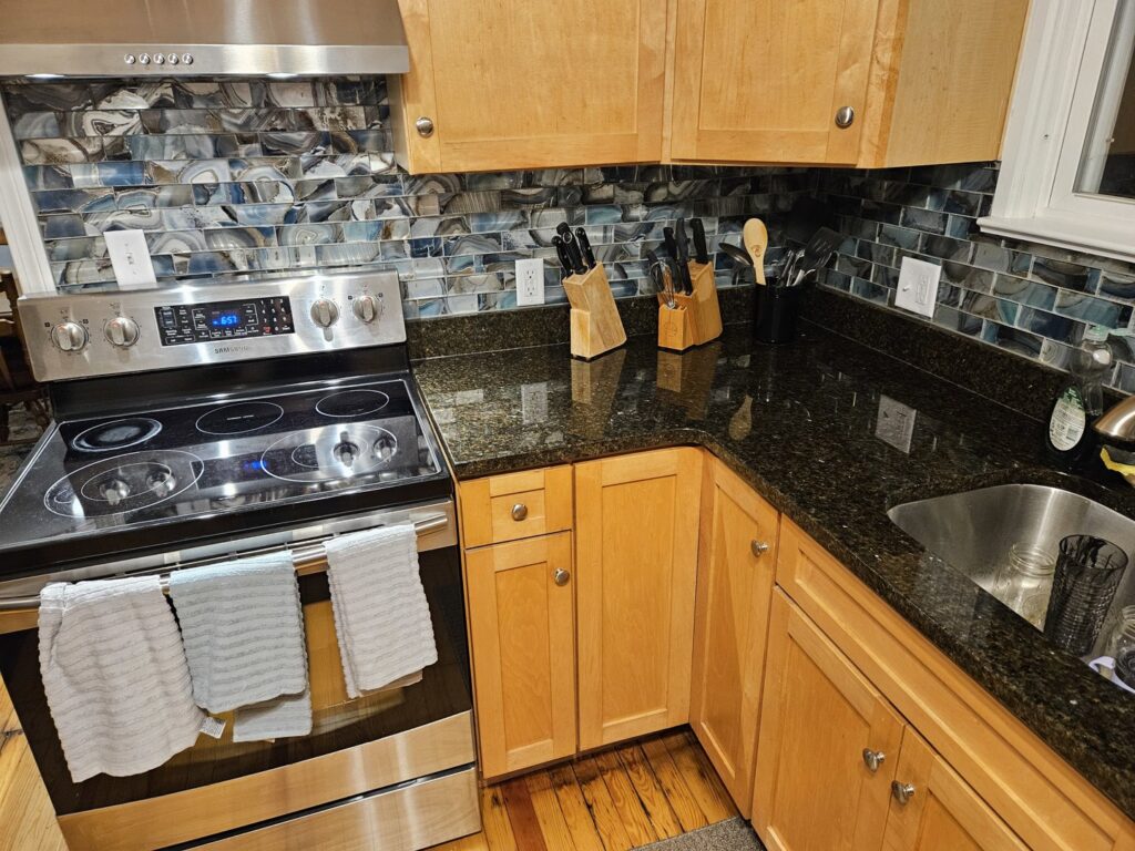 A kitchen with new blue tile backsplash and updated wooden cabinets by Garbatini Contracting in Wallingford, CT.