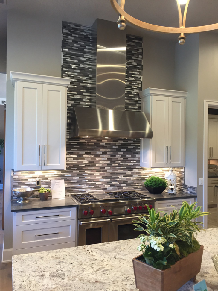 Modern kitchen with tiled backsplash, stainless steel range hood, and cabinet installation by T. Wheeler Homes, LLC in Salem, OR