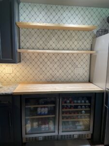 Kitchen area with new tile backsplash, floating wooden shelves, and beverage coolers installed by Absolute Integrity Handyman Services Inc in Fresno, CA.