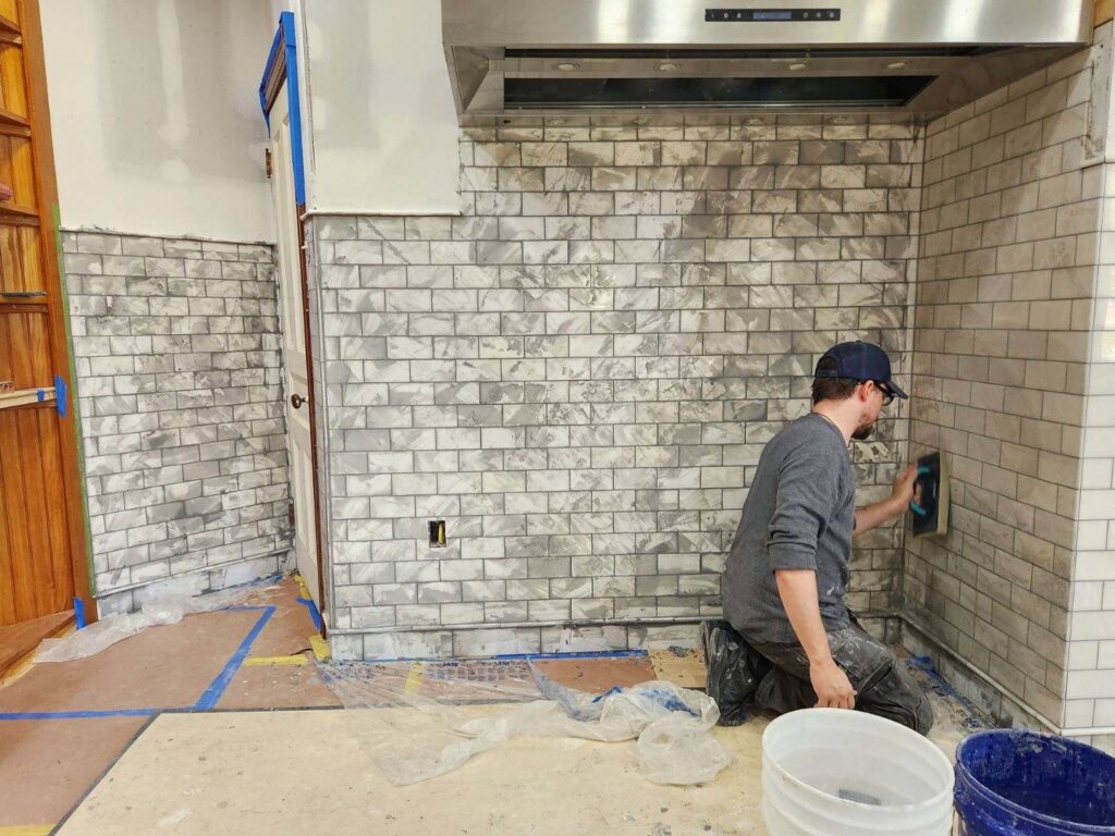 A general contractor installing subway tiles for a kitchen backsplash, showcasing detailed work by Ace Tile & Finishing LLC in Philadelphia, PA.