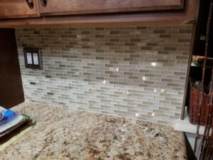 Newly installed kitchen backsplash with small rectangular tiles above a granite countertop by ALKA Construction/ Handyman Services in Layton, UT