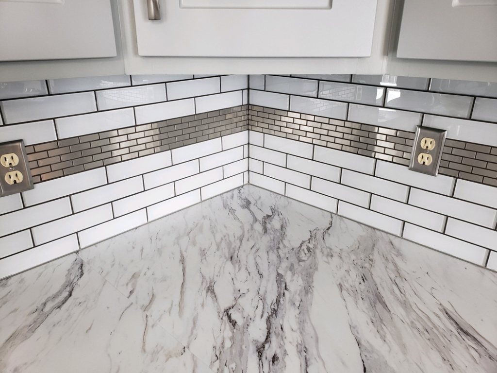 A newly installed kitchen backsplash with white subway tiles and a metallic accent strip by Bryan's Home Services in Fargo, ND.