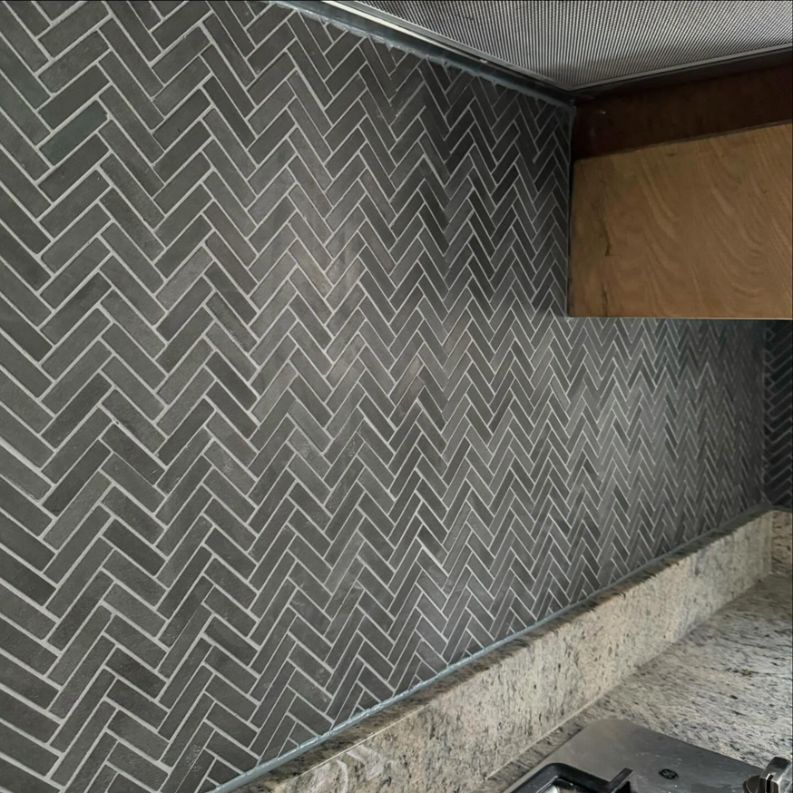 A newly installed dark grey herringbone tile kitchen backsplash by crystalwoodfloors in Port Jervis, NY