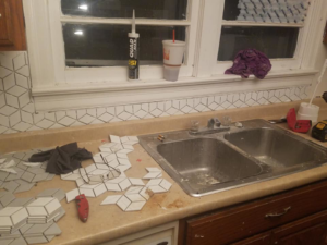 Geometric kitchen backsplash tile installation in progress above a sink, performed by Clayton's Remodeling And Home Services in Vero Beach, FL.