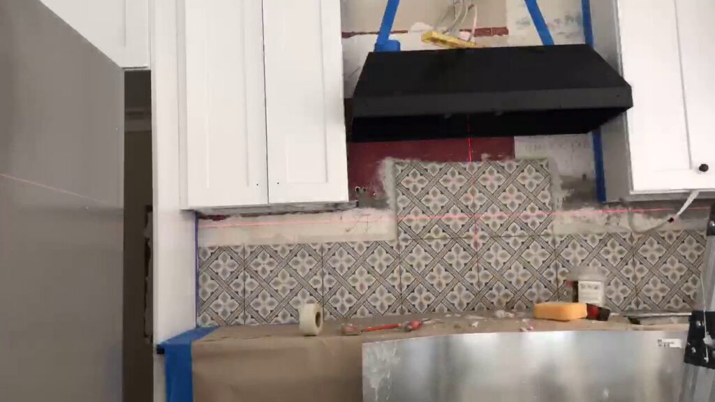 Kitchen backsplash tiling in progress with a laser level, showcasing work by Infinite Creations Construction, LLC in Denver, CO