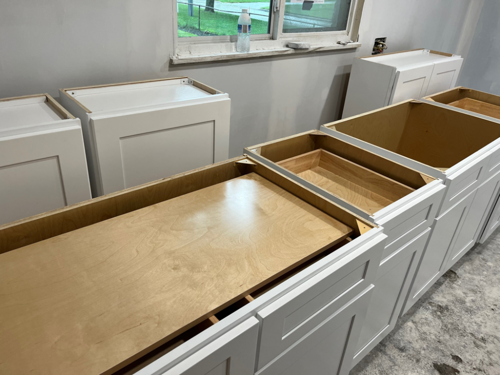 New white kitchen base cabinets being installed during a renovation project by Shifting Sands Contracting in Alvordton, OH.