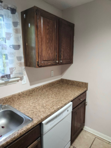 An older kitchen with dark cabinets and speckled countertops, ready for improvement by Wareham Home Improvements in Frederick, MD.