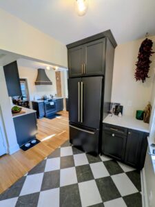 A remodeled kitchen featuring a striking black and white checkered floor and dark cabinets by CLE Remodeling Co in Cleveland, OH.