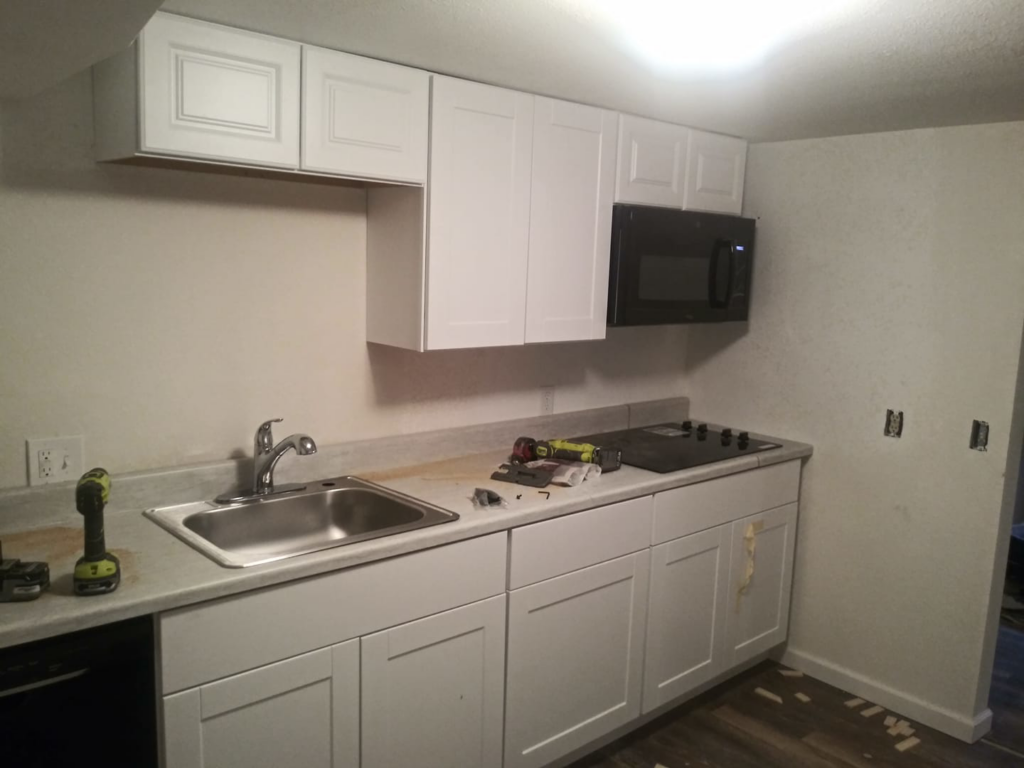 New kitchen cabinets, sink, and microwave being installed by Cali Painting in Fort Collins, CO
