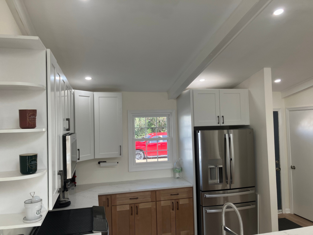 A renovated kitchen featuring white upper and wood lower cabinets, with a new stainless steel refrigerator by Precision Home Improvement in Virginia Beach, VA.