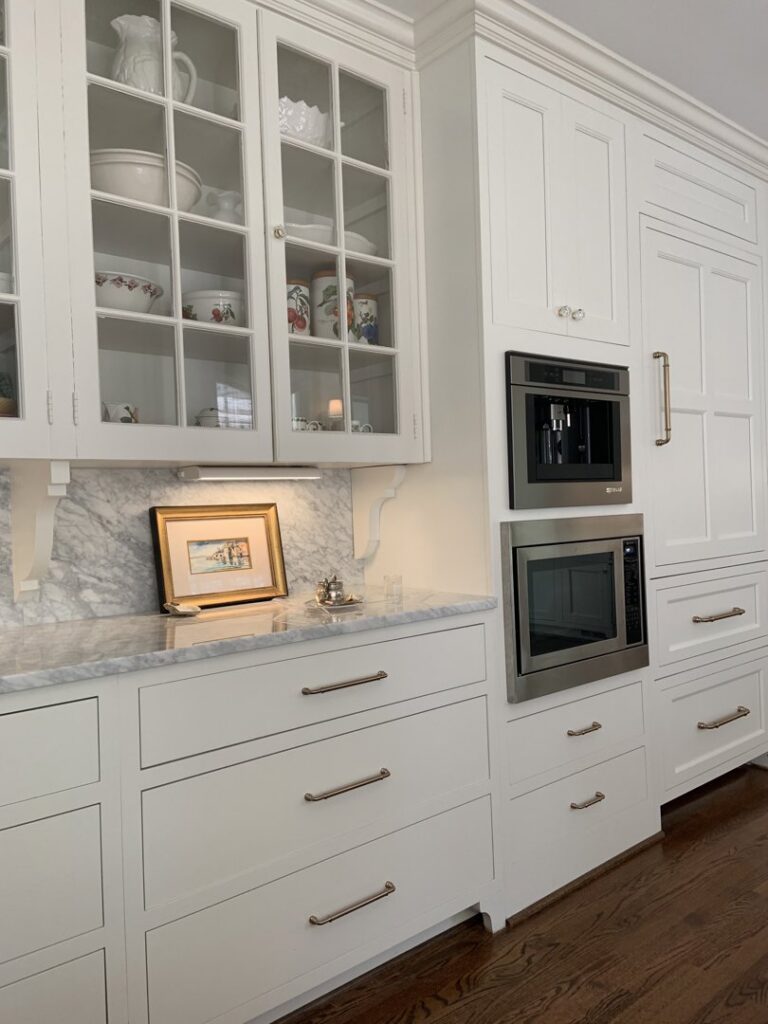 A custom white kitchen with built-in coffee maker, microwave, and elegant glass-front cabinets installed by Pro Finishes NC, LLC in Raleigh, NC.