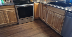 A renovated kitchen featuring new wooden cabinets, a stainless steel stove, and new flooring by Fairbanks Finest Handyman in Fairbanks, AK.