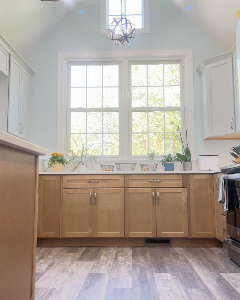 A newly installed kitchen with light wood cabinets, new flooring, and a modern light fixture by Home Style Improvement in Frederick, MD.