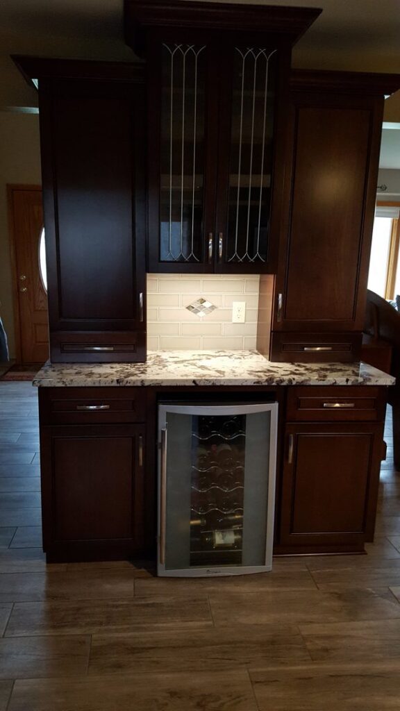 A completed kitchen installation featuring dark wood cabinets, granite countertop, and a wine fridge by Valiant Electric Inc. in Kenosha, WI.
