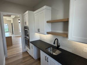 Kitchenette with white cabinets, black countertop, sink, and built-in ovens by ELS Construction in Springfield, MO.