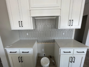 Kitchen with new white cabinets, countertops, and a tiled backsplash installed by Fueled Up Flooring- Justin Watruba in Eau Claire, WI.