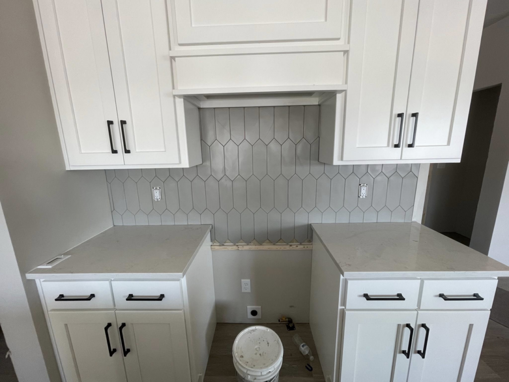 Kitchen with new white cabinets, countertops, and a tiled backsplash installed by Fueled Up Flooring- Justin Watruba in Eau Claire, WI.