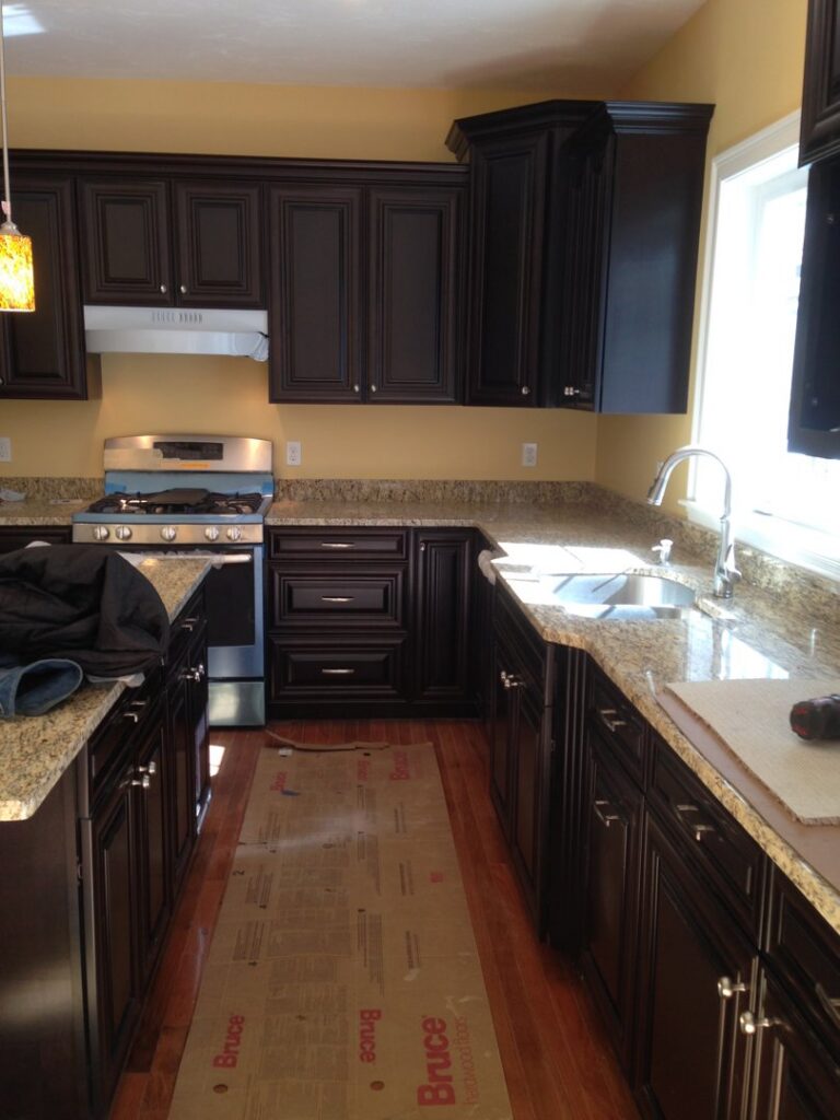 Kitchen renovation in progress with dark cabinets and granite countertops being installed by BizMick Construction in Coventry, RI.