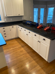 Handyman installing kitchen cabinets and black countertops with tools visible at CoCara Remodeling LLC in O Fallon, MO.