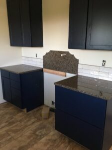 Kitchen renovation with dark blue cabinets, granite countertops, and subway tile backsplash installed by Fisher Construction, LLC in Selah, WA.