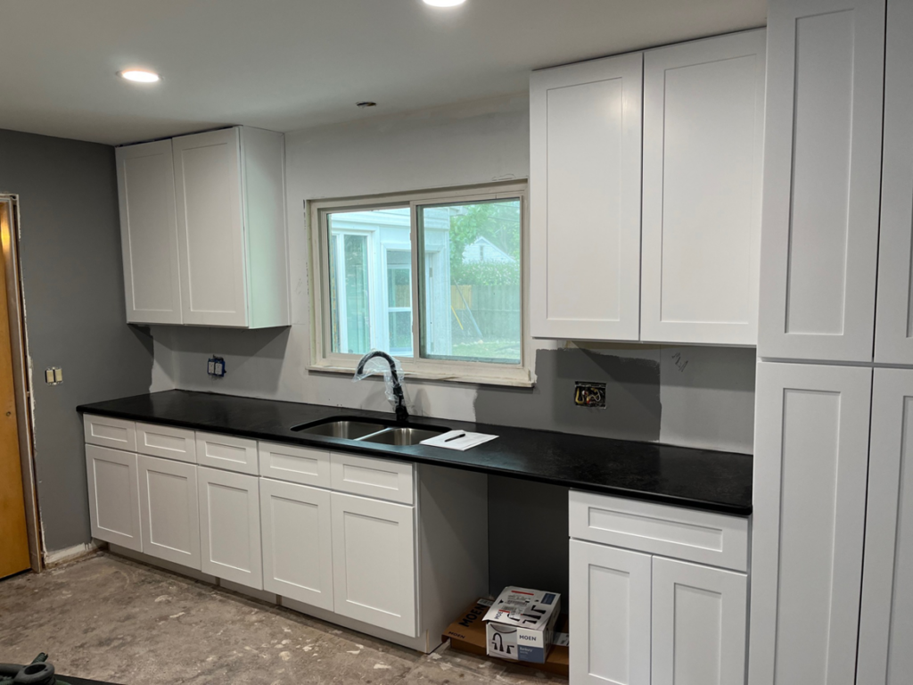 A kitchen renovation in progress with new white cabinets and black countertops installed by Shifting Sands Contracting in Alvordton, OH.