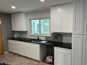 A kitchen renovation in progress with new white cabinets and black countertops installed by Shifting Sands Contracting in Alvordton, OH.