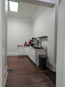 Newly installed white kitchen cabinets, countertop, and sink in a breakroom by Bourque's Quality Construction, LLC in Lafayette, LA.