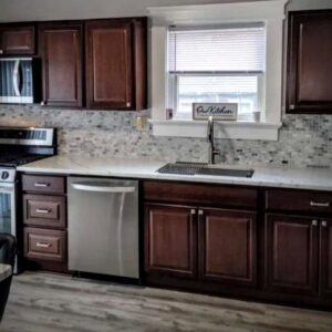 A renovated kitchen featuring dark wood cabinets, new countertops, and a tiled backsplash by Prime Construction And Flooring in Lorain, OH.