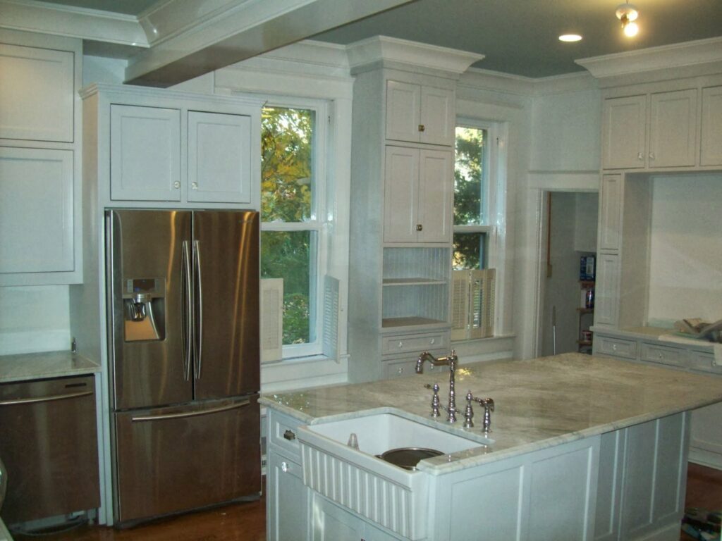 A newly installed kitchen with white cabinets and a large island by Custom Carpentry Service in Knoxville, TN.