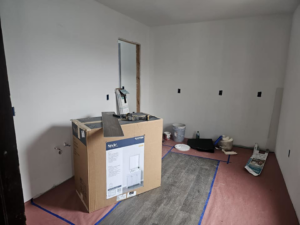 A room with new kitchen cabinets in a box and flooring materials, indicating renovation work by Done Well Home Improvement LLC in Buffalo, NY.