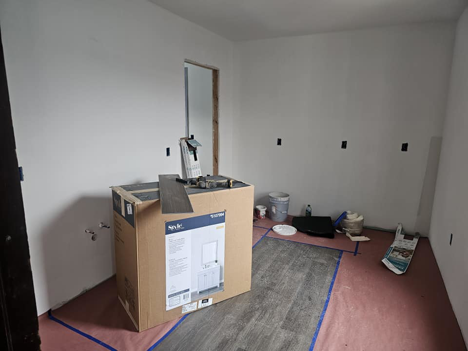 A room with new kitchen cabinets in a box and flooring materials, indicating renovation work by Done Well Home Improvement LLC in Buffalo, NY.